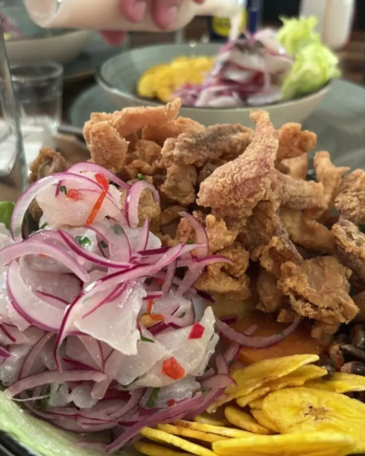 Leche de tigre being poured from a bottle over a ceviche