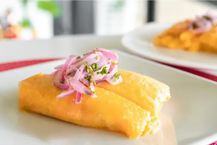 Peruvian tamal topped with salsa criolla